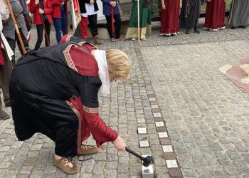 Salzwedels Bürgermeisterin Sabine Blüm setzt Steine mit den Namen der neuen Hansestädte in das Pflaster eines Platzes.