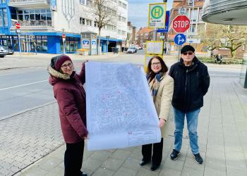 Margarete Strempel (Stadt Wesel, links), Bürgermeisterin Ulrike Westkamp und Friedhelm Heinzen (Behindertenbeauftragter der Stadt Wesel) präsentieren vor der Bushaltestelle "Großer Markt" die Umbaupläne samt Standorte der 17 Bushaltestellen in Wesel. Diese werden zeitnah barrierefrei ausgebaut. 