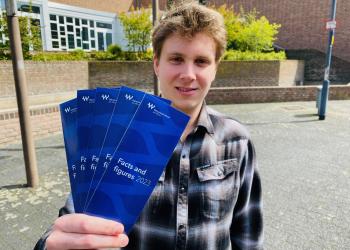 Der Ausszubildende Niklas Wilken stellt im Rathausinnenhof die neuen, übersetzten Flyer vor.