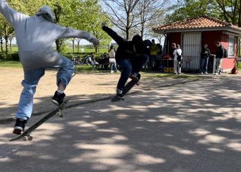 Zwei junge Männer zeigen mit ihren Skateboards Tricks. 