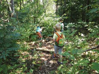 Abenteuer Stadtranderholung Kind mit Rucksack im Wald