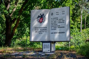 Ehrenmal des Schützenvereins Wesel-Feldmark Vorm Clever Tor Ehrenmal stellt ein aufgeschlagenes Buch dar, welches auf einem würfelförmigen Sockel steht