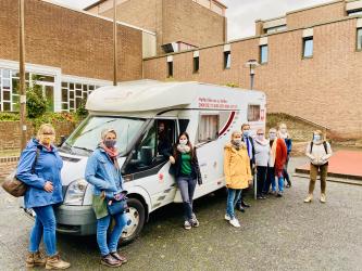 Mitglieder der Arbeitsgruppe Sozialraum vor einem Wohnwagen 