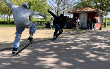 Zwei junge Männer zeigen mit ihren Skateboards Tricks. 